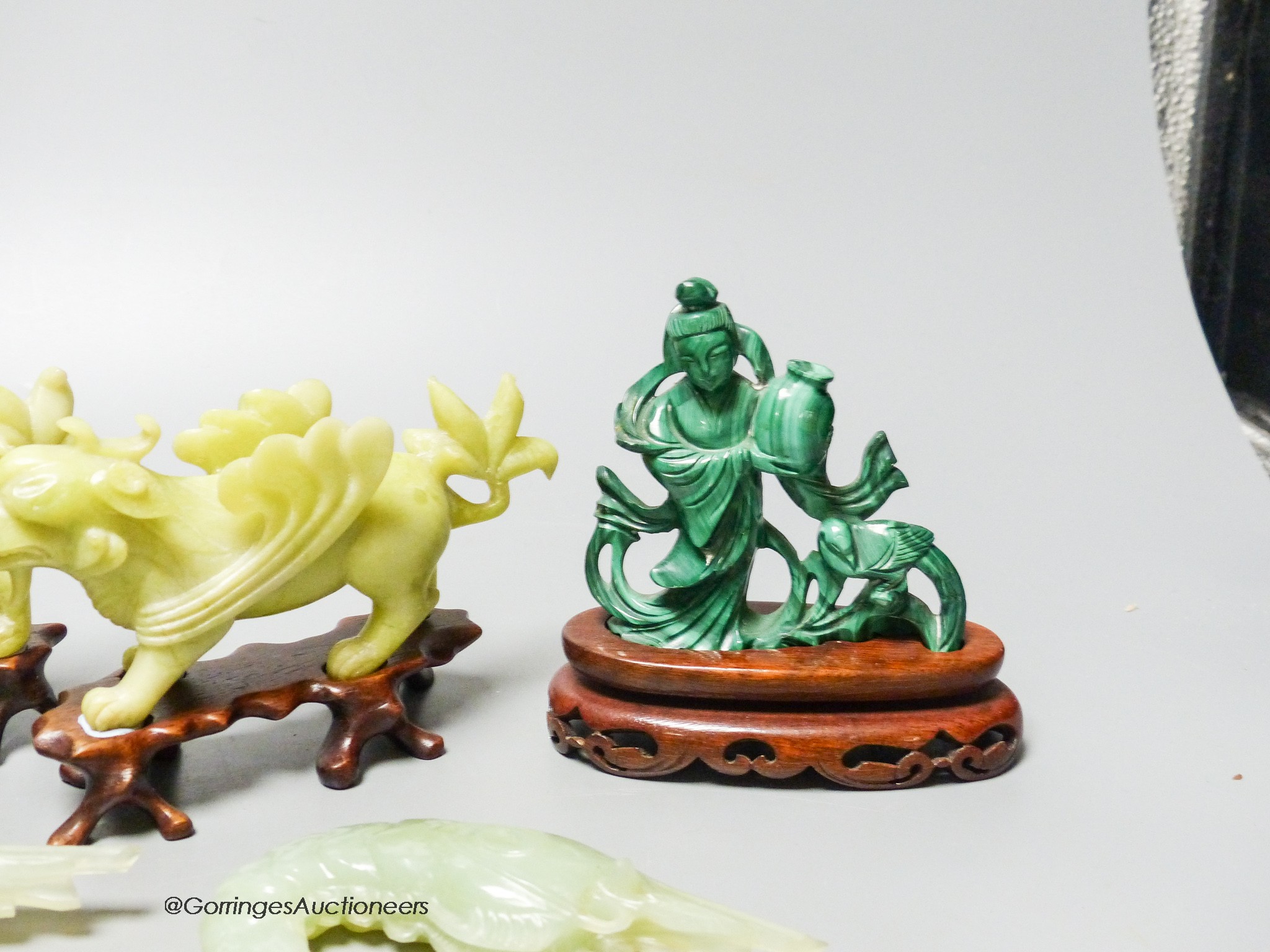 A group of Chinese hardstone carvings, mid 20th century to include a pair of mythical beasts, a pair of bowenite jade figures of tiger prawns and a malachite figure of a lady, three wood stands